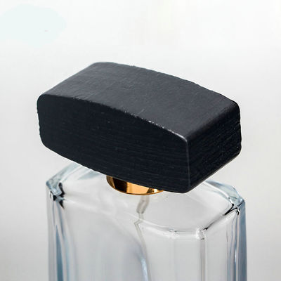 Empty glass perfume bottle with cap and pump spray collarwith wooden black cap